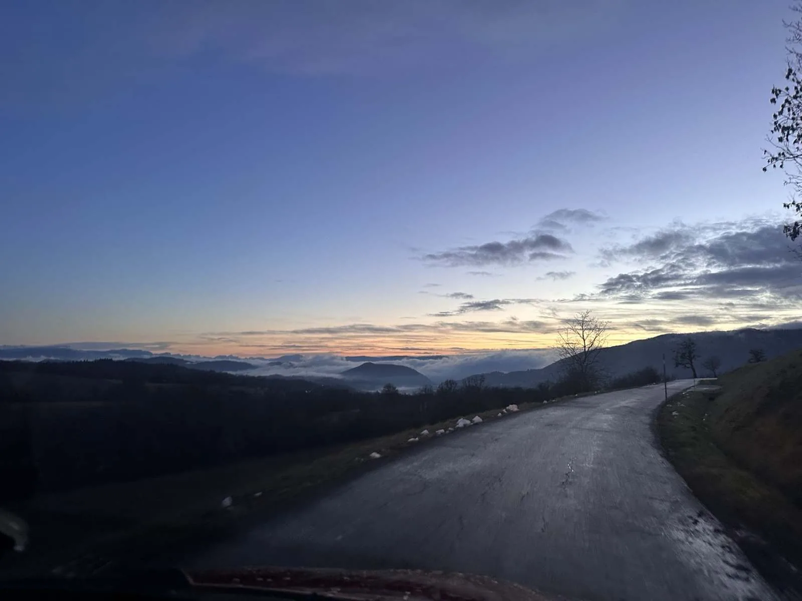 Route de montagne au crépuscule, brume dans la vallée