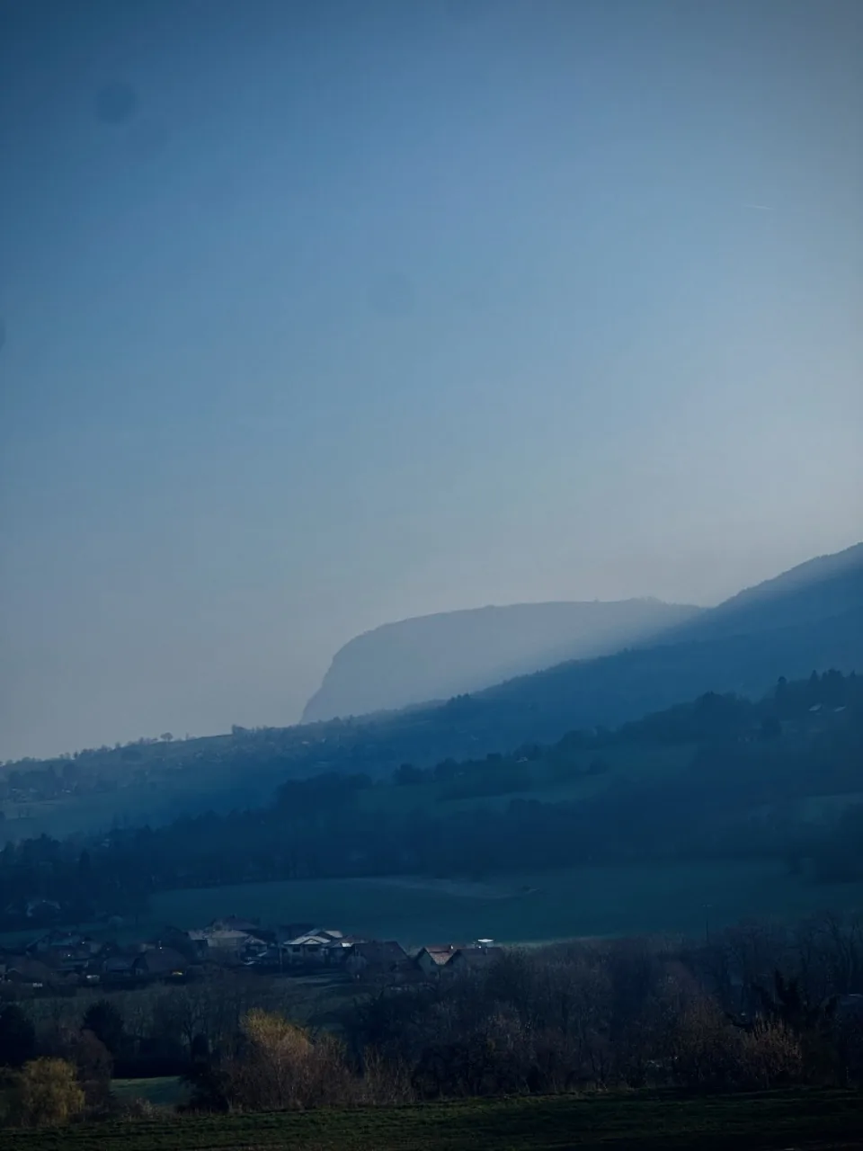 Village et champs sous la montagne dans la brume